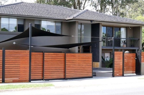 Wood slat telescopic sliding gate in front of large home