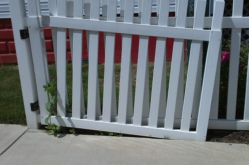 An slate grey vertical slate swinging gate that is badly sagging